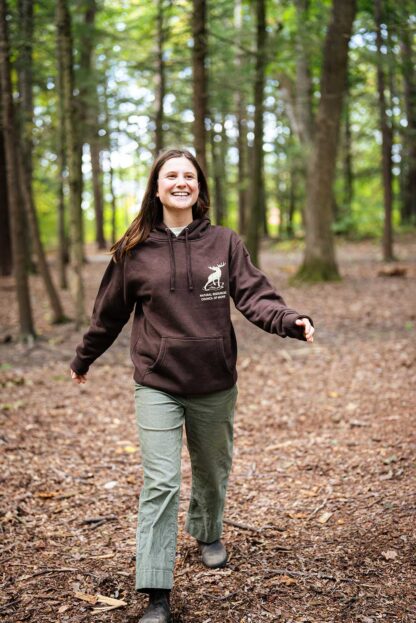 smiling person in woods wearing sweatshirt